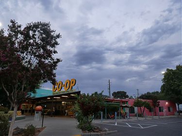A photo showing cumulonimbus clouds above a grocery store with a large yellow sign reading "CO-OP" on its roof.