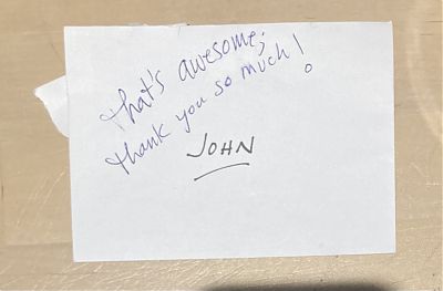 photo of an enveloped marked John, where a note has been written in blue pen, saying That's Awesome, thank you so much!