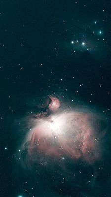 An astrophotograph showing a large pink and greenish nebula towards the bottom of the image and a smaller reflection nebula around some stars toward the top of the image.