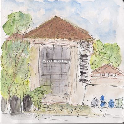 An line and wash sketch of a two-story building with a peaked red tile roof and trees on either side with an unsettled sky