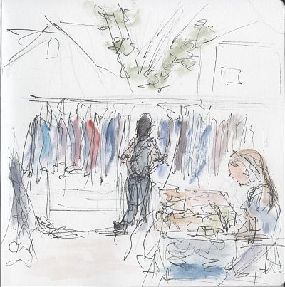 A pen and wash sketch of an outdoors market stall. In the lower right corner a woman is seated at a table tending shop. Towards the back, another woman is browsing a clothes rack.