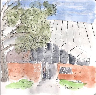 A pen and wash sketch of a two story building with a tree in front of it on its left. A sign on the left side of its entrance reads Lower Freeborn Entrance and on the righthand side a sign reads Davis Calif kdvs 90.3 freeform radio 